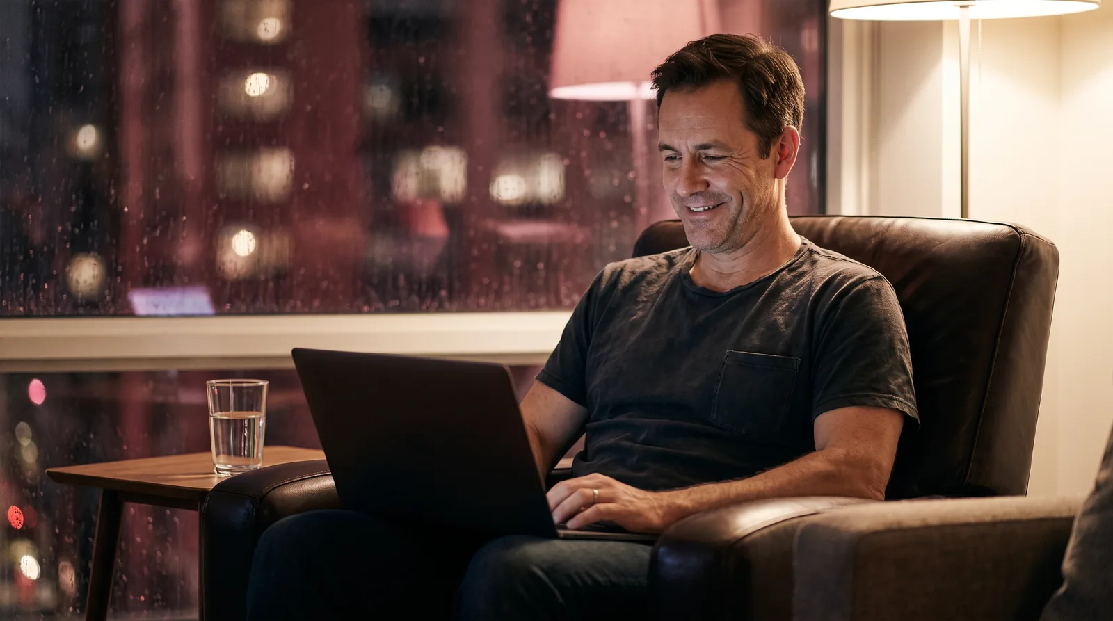 Man smiling at a private chat on his laptop at home in the evening